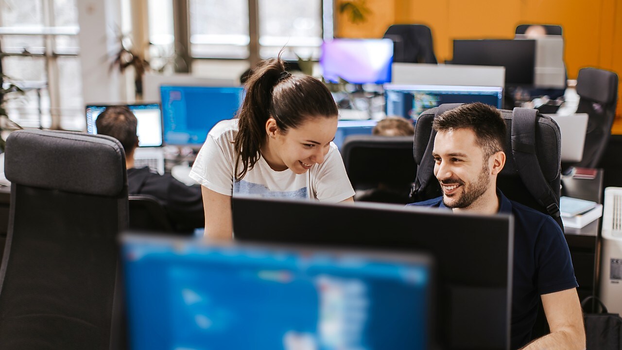 Two colleagues collaborating at a computer workstation in a office