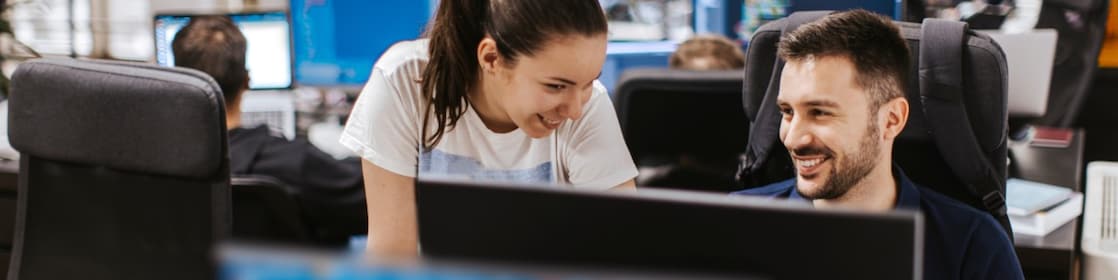 Two colleagues collaborating at a computer workstation in a office