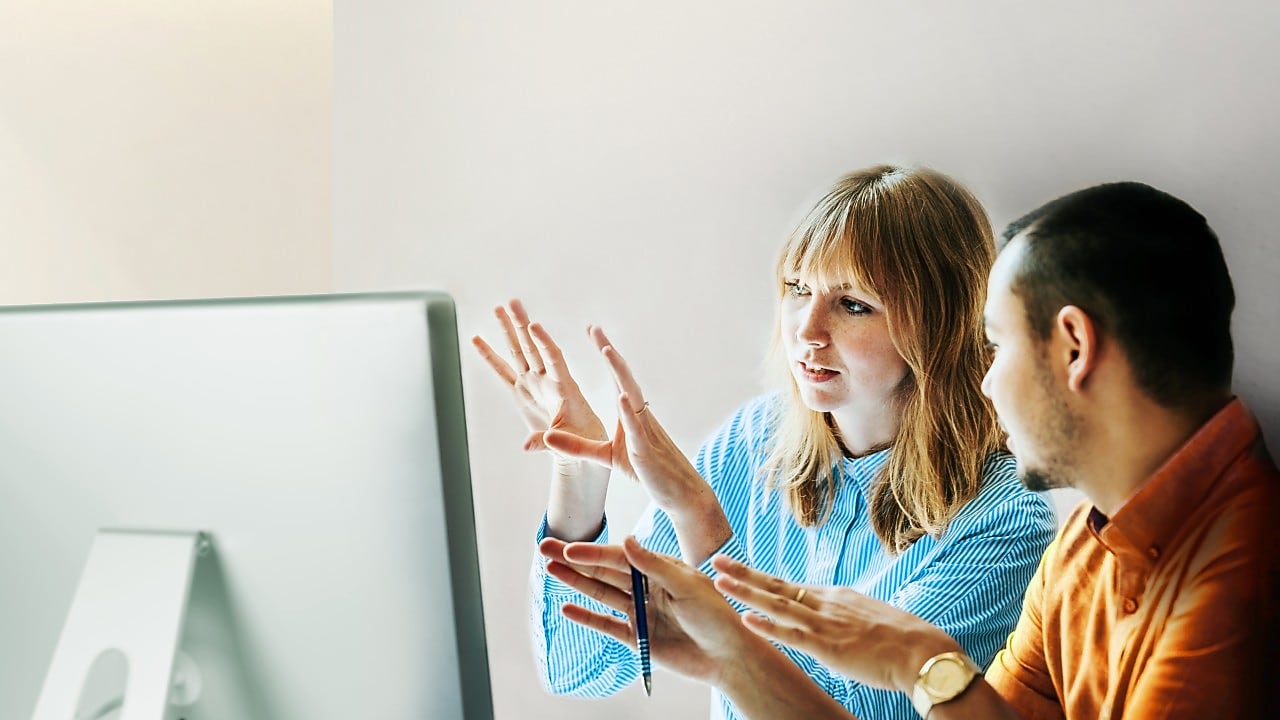 Two employees working together in front of a desktop