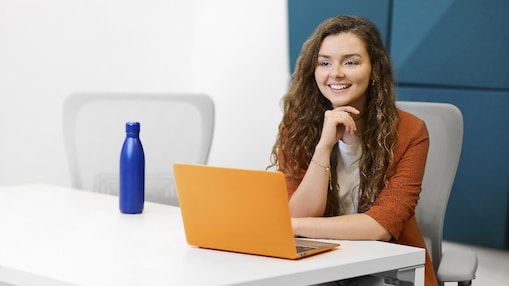 A smiling woman sitting at a table with a computer in front of her