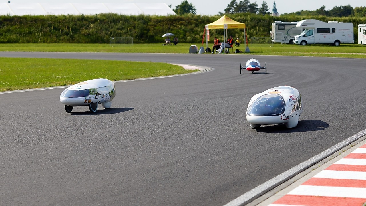 trzy bolidy ścigajace się na torze wyścigowym