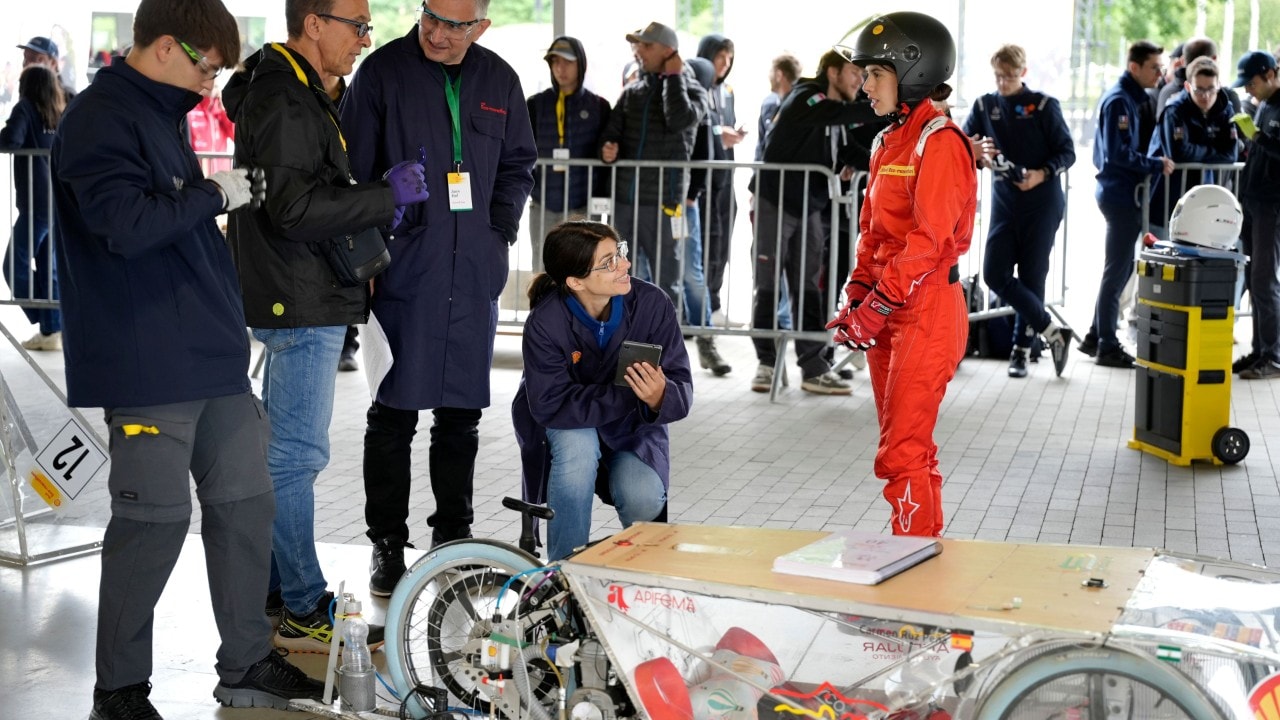 pieć osób stojących nad bolidem dokonujących inspekcji technicznej