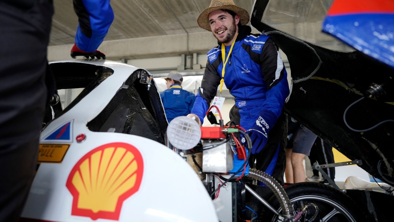 uśmiechnięty student sprawdza silnik bolidu