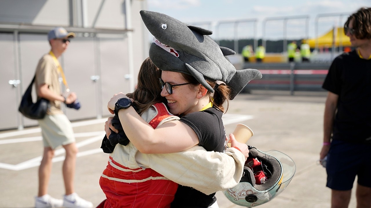 studentka w czarnym kombinezonie wyścigowym i białym kasku