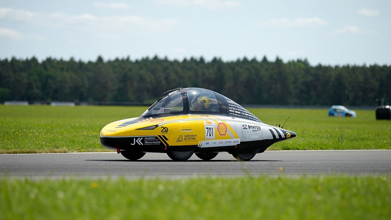 żółty bolid poruszający się po torze wyścigowym