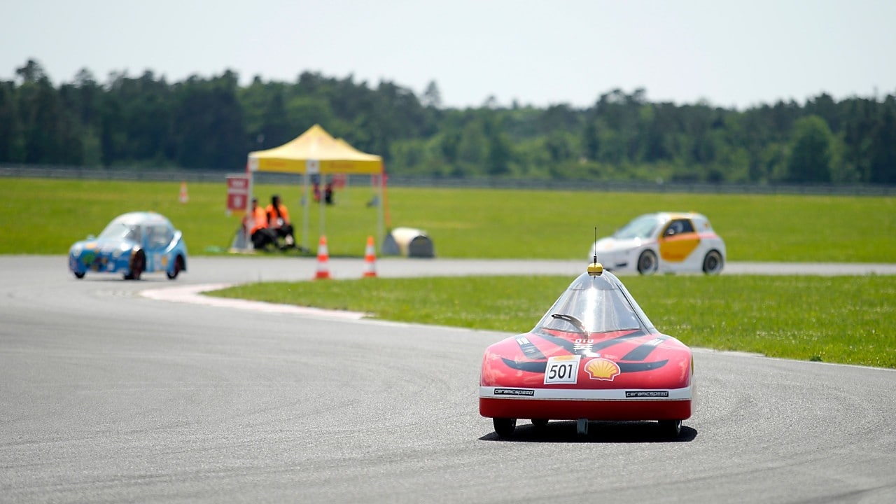 trzy bolidy ścigajace się na torze wyścigowym