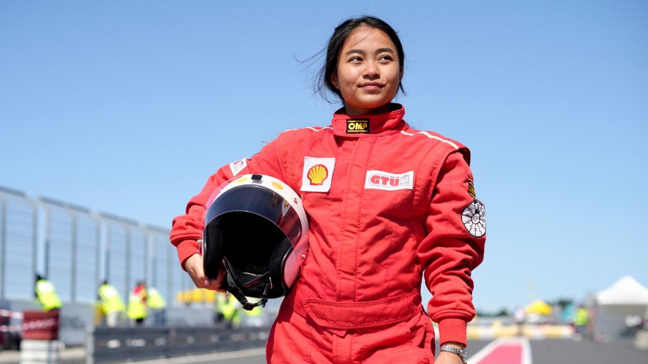 uśmiechnięta studentka w czerwonym kombinezownie i białym kaskiem pod ręką