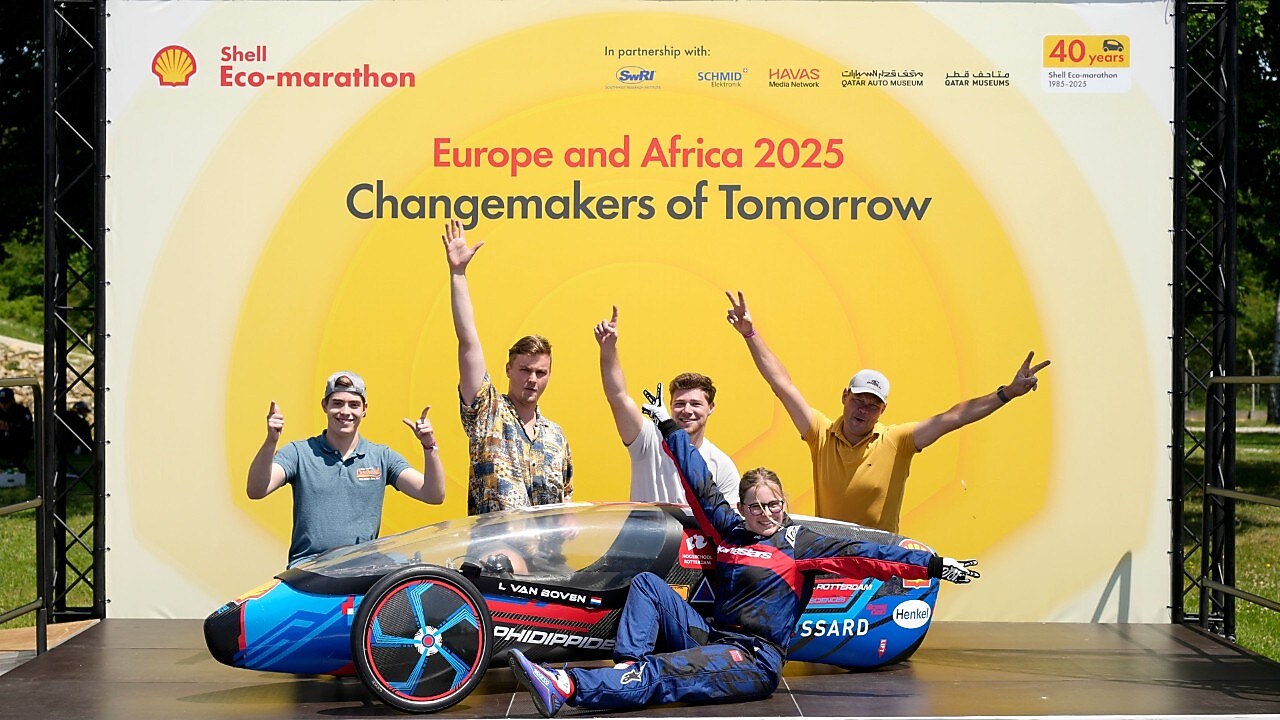 piątka studentów stoi na scenie z niebiesko-czarny bolidem