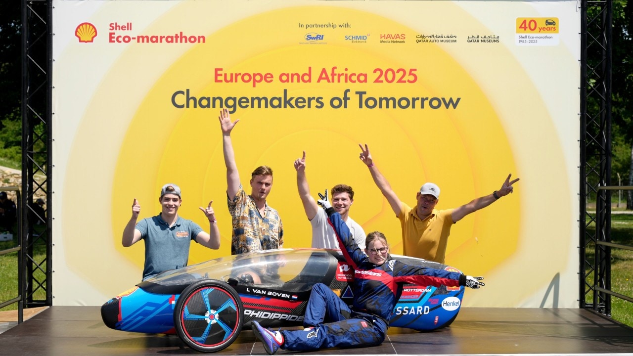 piątka studentów stoi na scenie z niebiesko-czarny bolidem