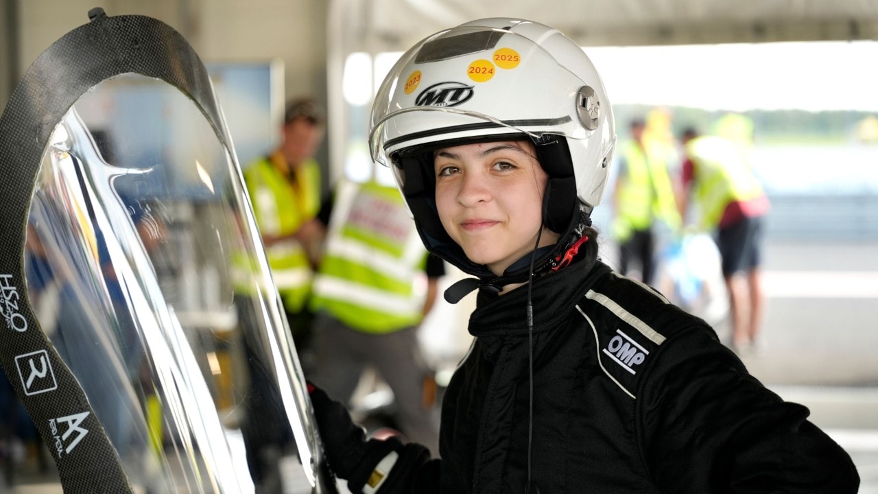 dwie świętujące studentki przytulają sie, jedna ma czapkę w kształcie rekina