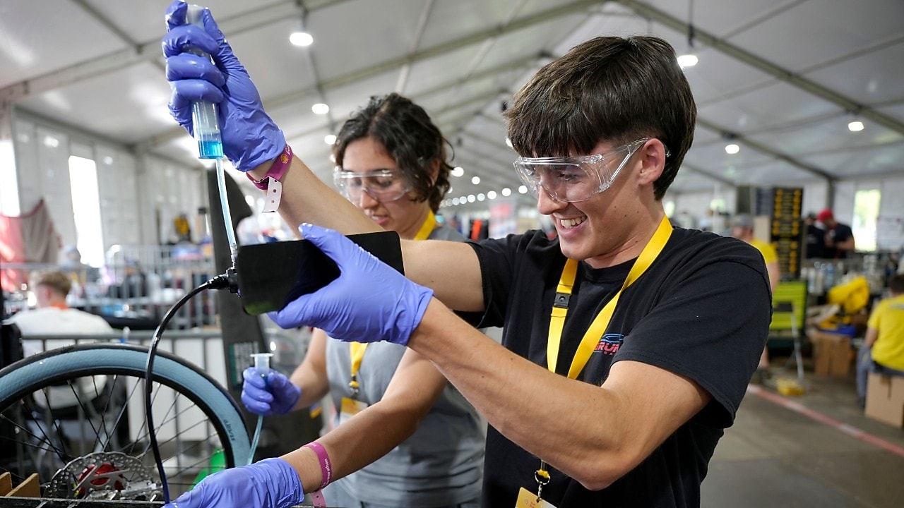 studenci w okularach ochronnych uzupełniają zboiornik z paliwem 