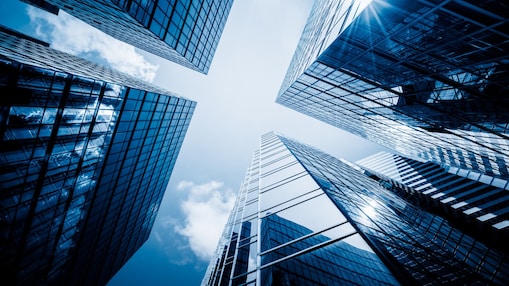 Widok na niebo pomiędzy odbijającymi światło budynkami