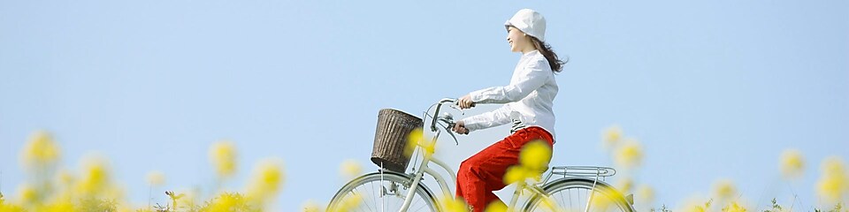 Młoda kobieta jedzie na rowerze przez pola latem