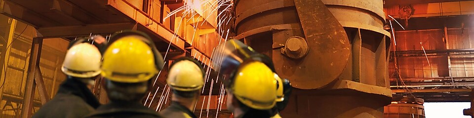 pracownicy nadzorujący ciężki sprzęt w zakładzie metalurgicznym