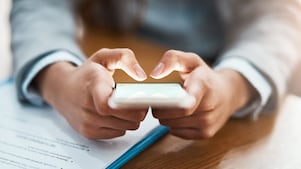 Two hands shown using a mobile device to send an email