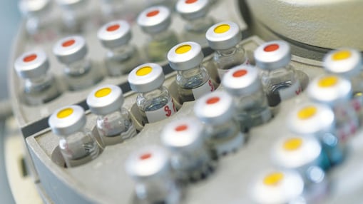 Rows of medicine vials sitting in a holder, some with red dots on the lid, and some with yellow dots on the lid