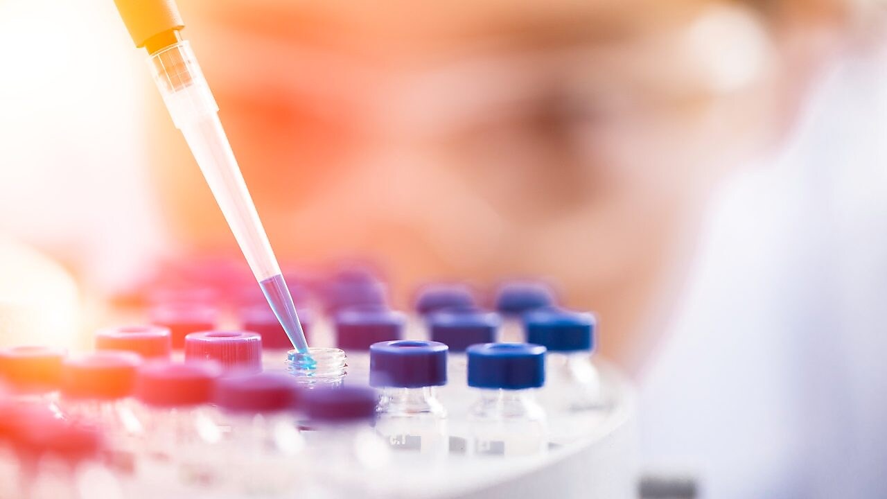 Liquid being poured into a plastic funnel by a shell scientist in a laboratory