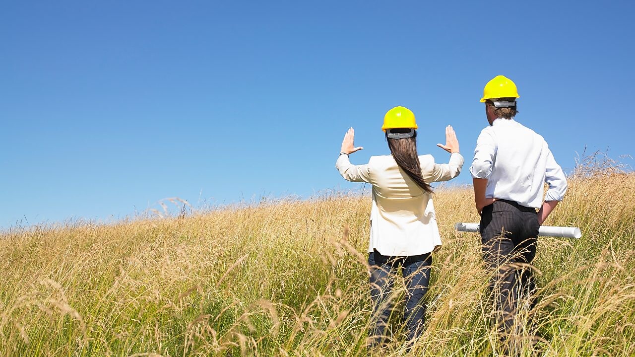 Dwóch robotników w kaskach z widokiem na pole