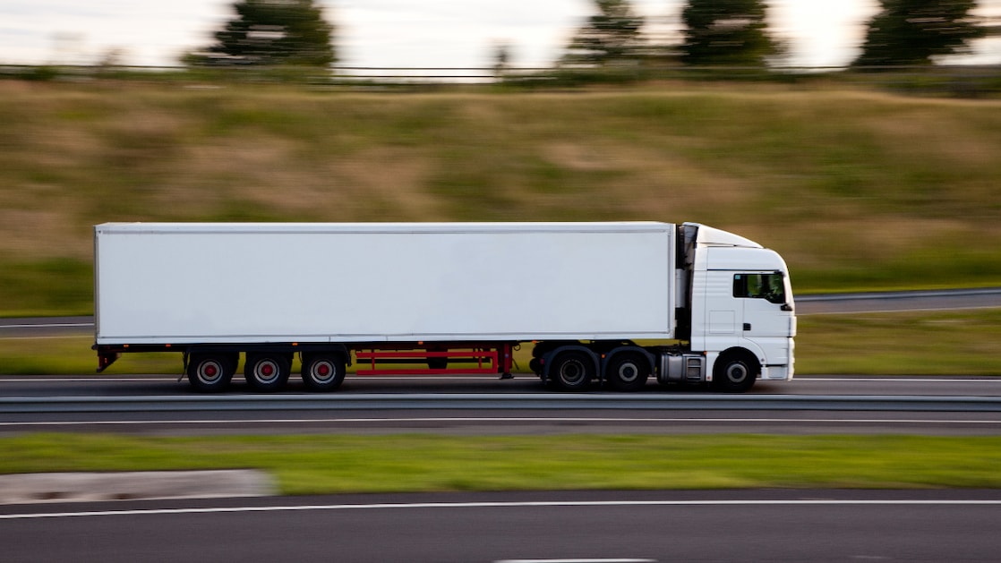 Ciężarówka na autostradzie, rozmazany ruch, widać ciężarówkę jadącą drogą.