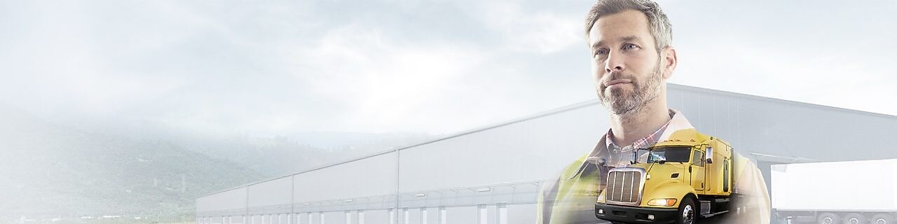 mężczyzna czytający dokumentację na tle żółtej ciężarówki w terenie