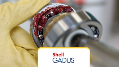 Zbliżenie makro – łożysko toczne pokryte żółtym, przezroczystym smarem litowym, na białym tle, z miejscem na tekst; koncepcja inżynieryjna i przemysłowa.