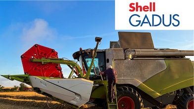 Osoba wspina się po schodkach dużego kombajnu na polu – smary Shell Gadus