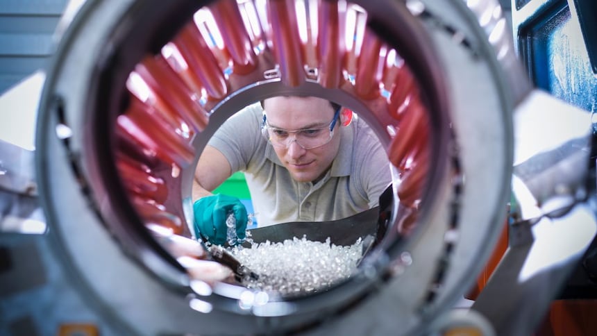 Man scooping plastic pellets into a mixing machine
