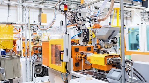 Horizontal color image of automated injection moulding machine working on plastic parts production. Powerful molding machinery in factory arranged in a row.
