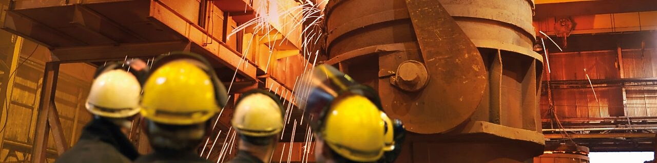 pracownicy nadzorujący ciężki sprzęt w zakładzie metalurgicznym