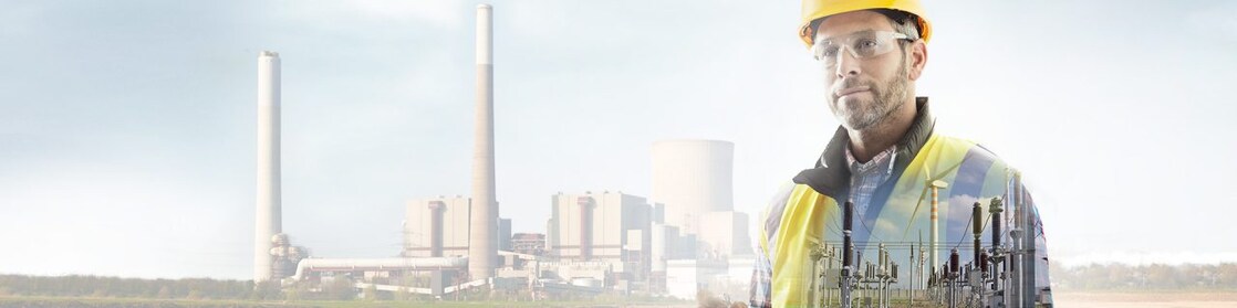 Pracownik w żółtym kasku na tle elektrowni