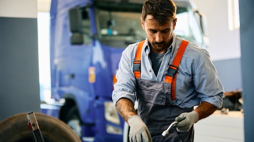 Mechanik używający narzędzi do pracy przy ciężarówce w warsztacie do pojazdów ciężarowych.