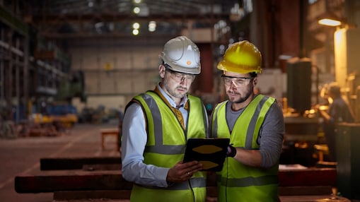 male engineer and worker using digital tablet in dark factory