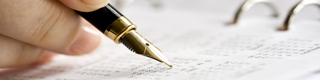 Harmonogram czasu pracy kierowcy – zasady tworzenia. Otwarty kalendarz i ręka z piórem.