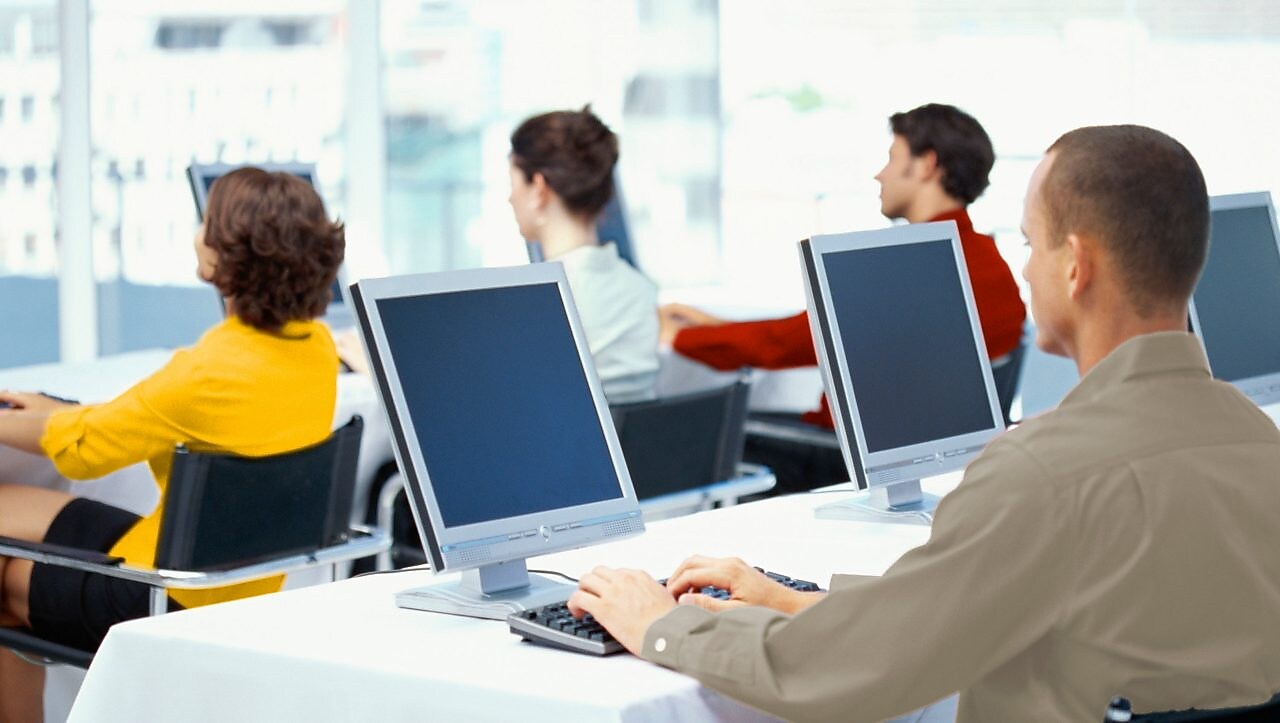 rear view of four business executives using computers in an office