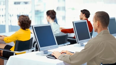 rear view of four business executives using computers in an office