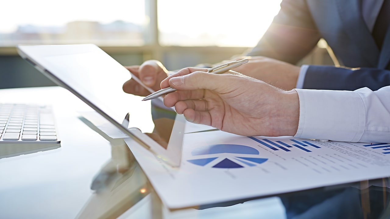 Wyliczanie TCO – fleet managerwie analizują informacje z tableta i wykresów w formie papierowej.