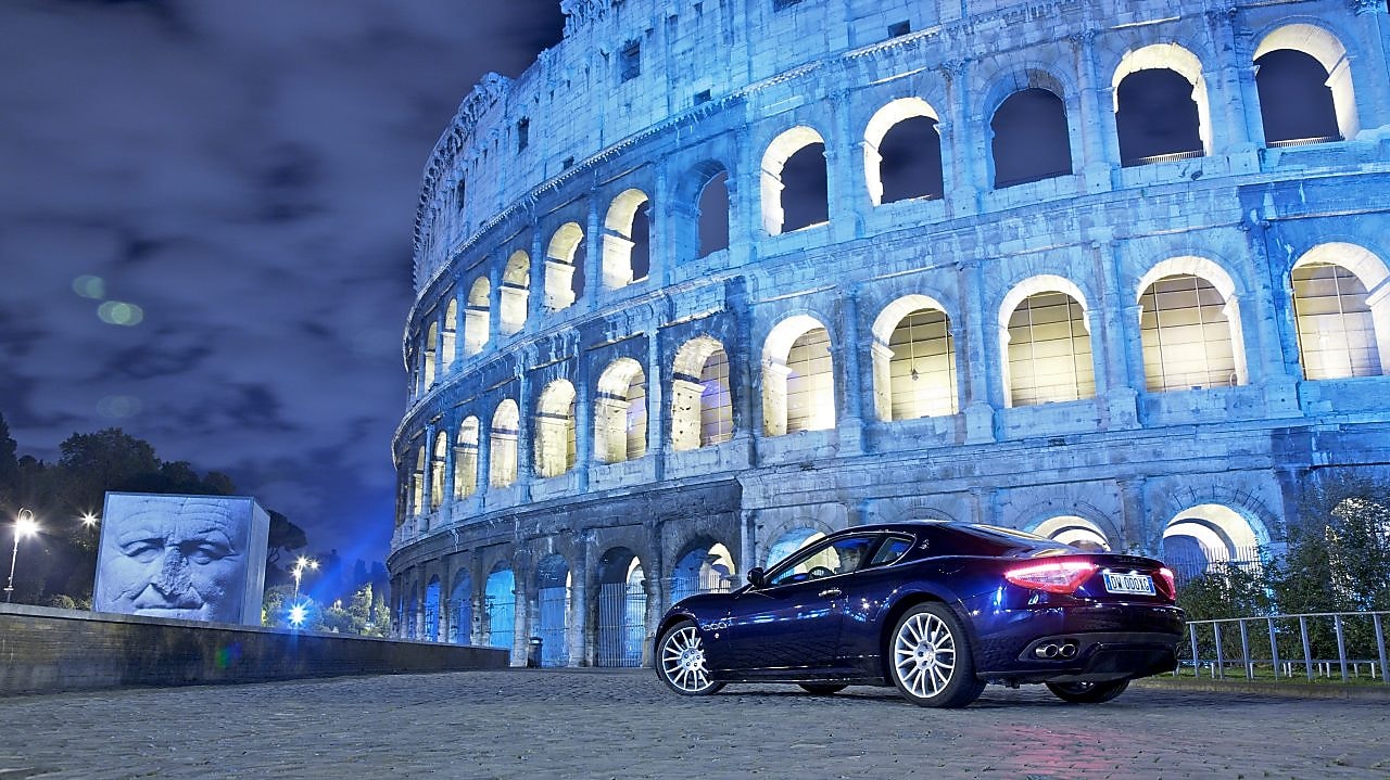 Czarny samochód nocą przed Koloseum