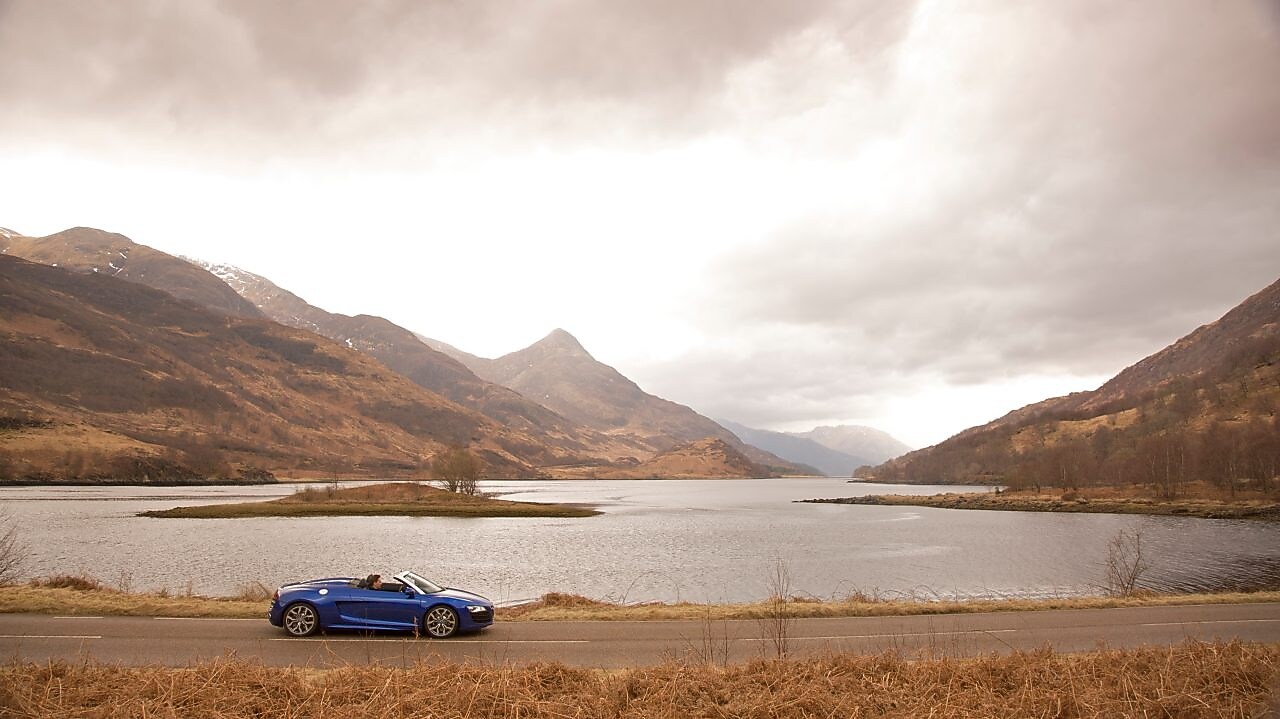Niebieski samochód jadący brzegiem jeziora