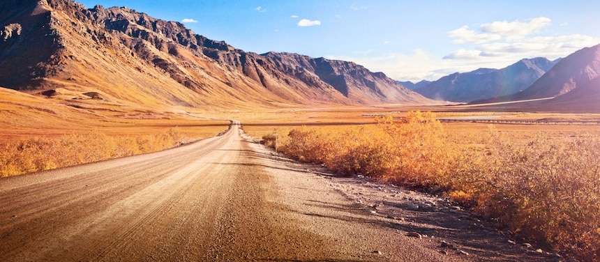 Deserted dirt road running through a mountainous valley