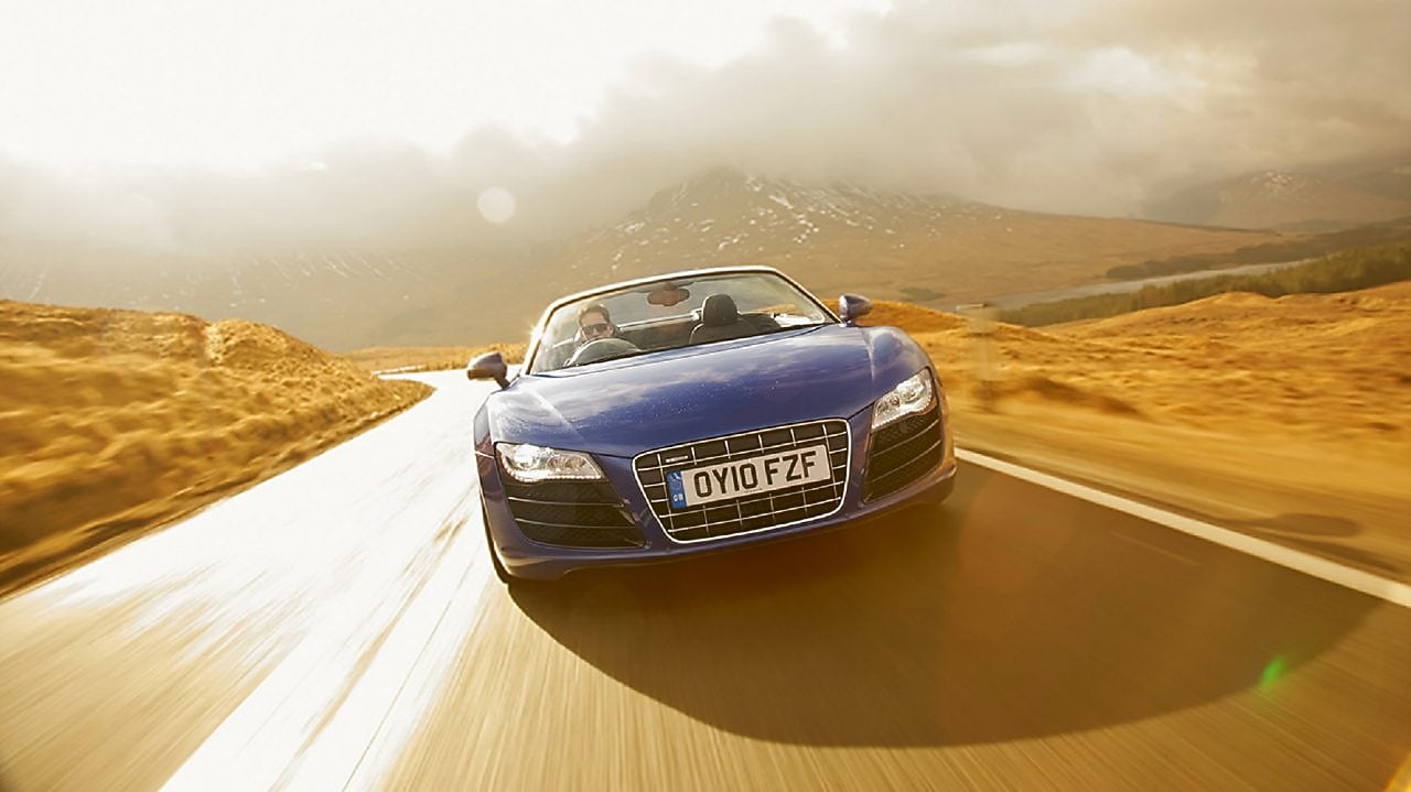 Niebieski kabriolet jadący przez tereny wiejskie w górskiej scenerii