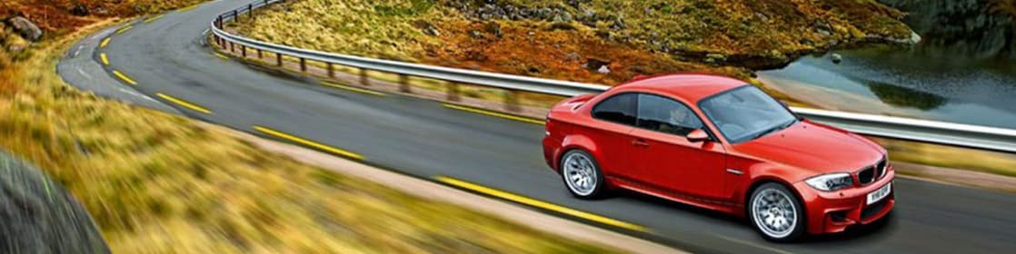 Czerwony sedan na wijącej się górskiej drodze w Norwegii