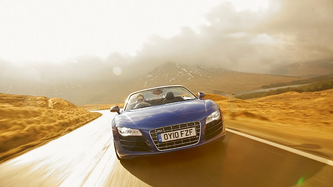  Niebieski kabriolet jadący przez tereny wiejskie w górskiej scenerii