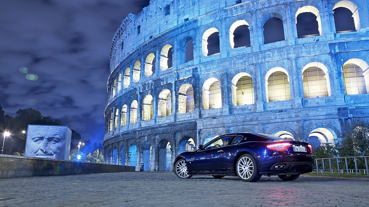 Samochód zaparkowany nocą przed Koloseum w Rzymie
