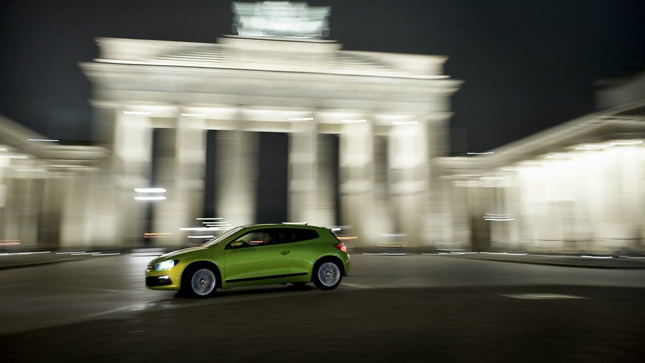 Mknący ulicami zielony samochód nocą