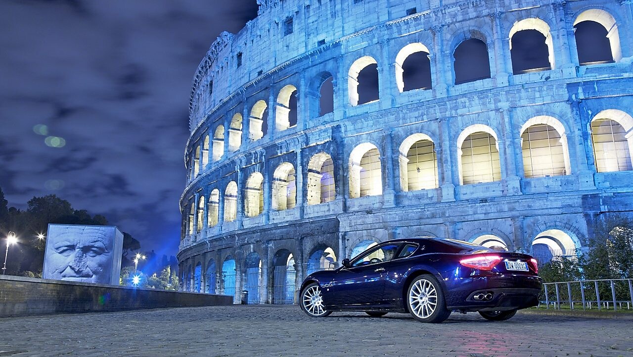 Samochód zaparkowany nocą przed Koloseum w Rzymie