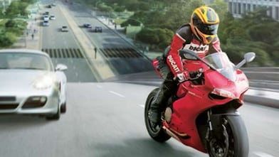 Czerwony motocykl i motocyklista na drodze między samochodami z budynkami w tle