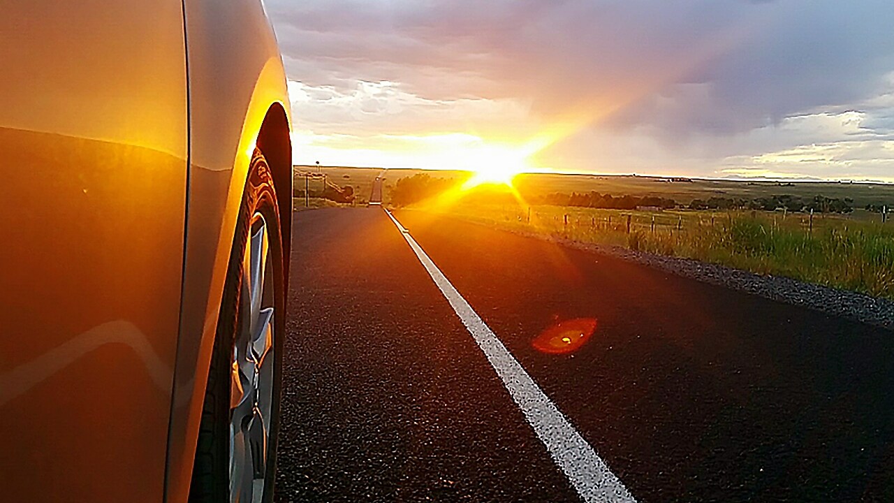 Koło samochodu w tle zachodzące słońce