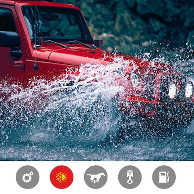 Czerwony Jeep z pluskiem przejeżdża przez koryto rzeki, pokazując zalety wydajnego w skrajnych temperaturach produktu.