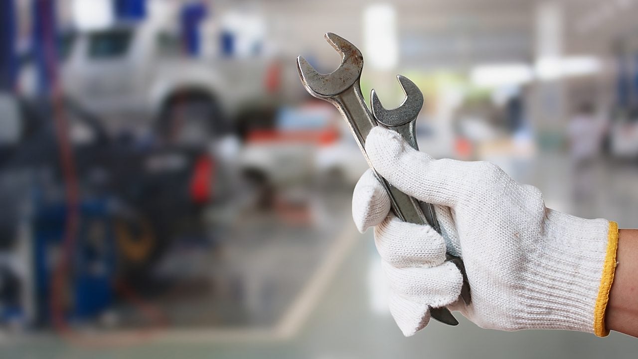 ręka z kluczem na tle warsztatu samochodowego