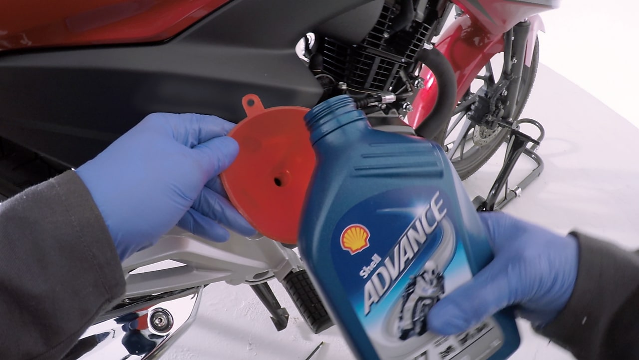 ręce trzymające nowy olej motocyklowy Shell Advance